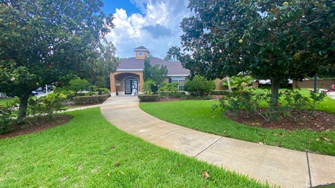 Club House Entrance with long sidewalk surrounded by trees