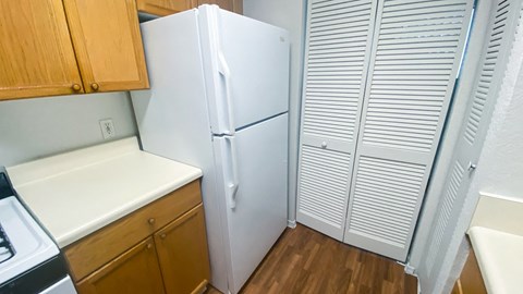 A white refrigerator is in a kitchen with wooden cabinets.