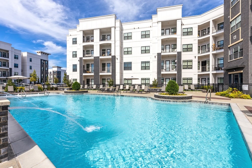 A large swimming pool in front of a white apartment building.