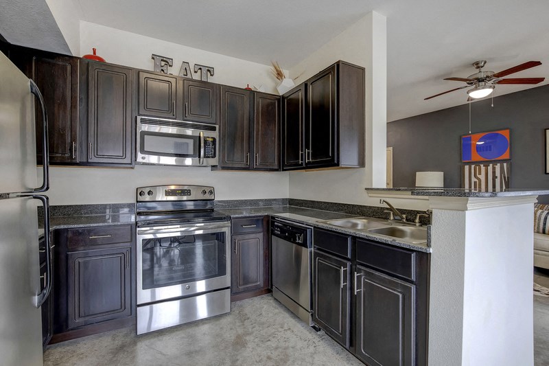 an empty kitchen with stainless steel appliances and dark wood cabinets