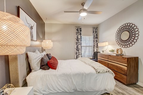 A bedroom with a white bed and a wooden dresser.