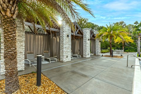 a patio with chairs and palm trees in front of a building