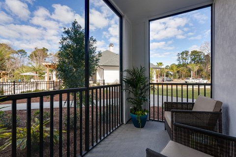 a balcony with chairs and a plant and a large window