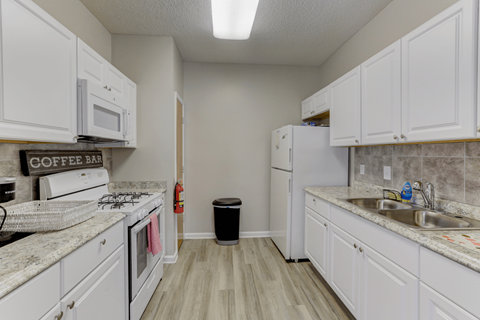 A kitchen with white cabinets and a coffee sign on the counter.