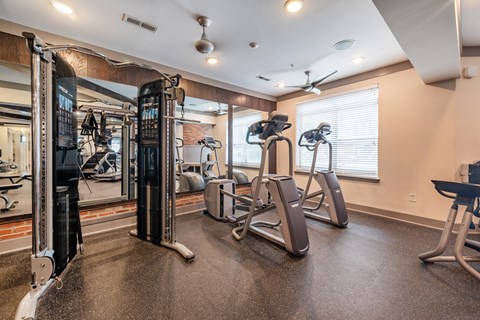 A gym with a variety of equipment including treadmills, weights, and exercise machines.