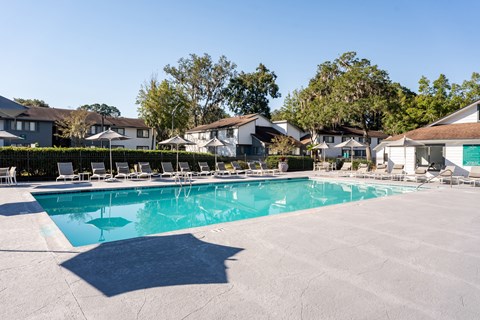 A large swimming pool surrounded by lounge chairs and houses.