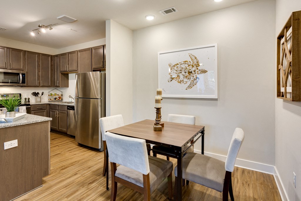 a dining room with a table and chairs and a kitchen with stainless steel appliances