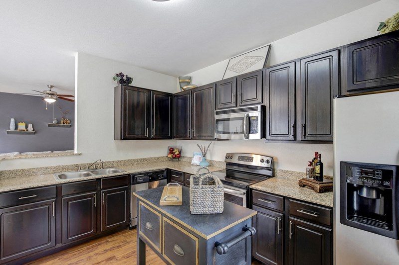 a kitchen with black cabinets and stainless steel appliances and granite counter tops