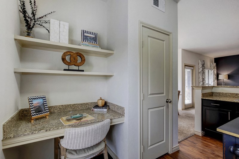 an office with a desk and a door to a living room