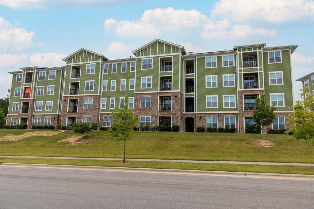 A large green apartment building with a tree in front at Foxwood Apartments, Raleigh-Durham