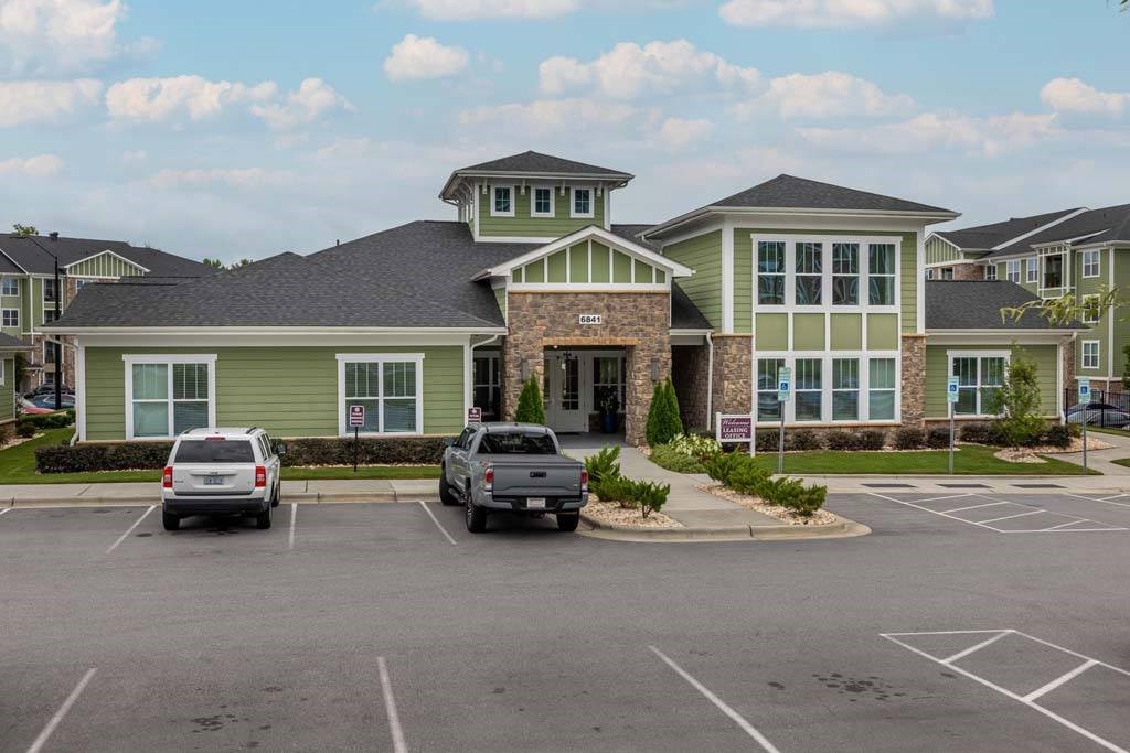 A parking lot in front of a building with a green and grey exterior at Foxwood Apartments, North Carolina, 27616