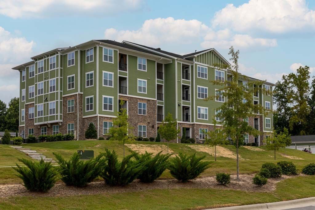 A large green apartment building with a grassy front yard at Foxwood Apartments, North Carolina