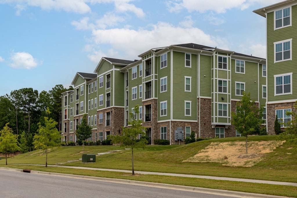 Apartment building with green and grey exterior on a sunny day at Foxwood Apartments, Raleigh-Durham, North Carolina