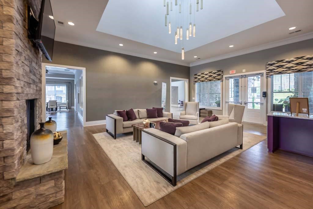 A modern living room with a stone fireplace and a large chandelier at Foxwood Apartments, Raleigh-Durham, 27616