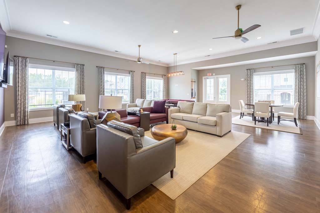 A spacious living room with a variety of seating options and a large rug at Foxwood Apartments, Raleigh-Durham, NC