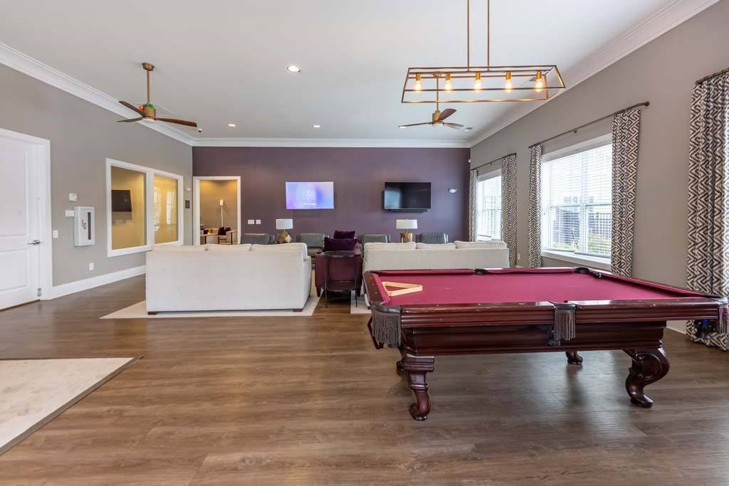 A pool table is in the middle of a room with a television and a couch at Foxwood Apartments, Raleigh-Durham
