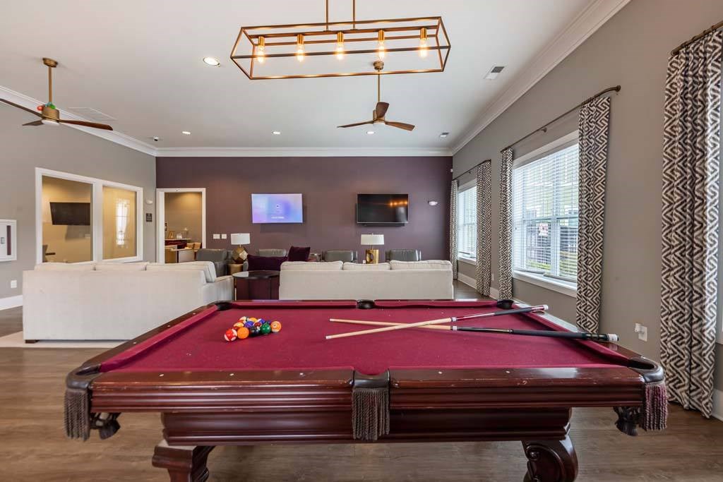 A pool table is in the middle of a room with a television and a fan at Foxwood Apartments, Raleigh-Durham