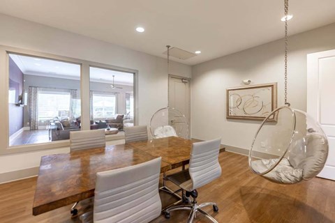A modern dining room with a wooden table and white chairs.