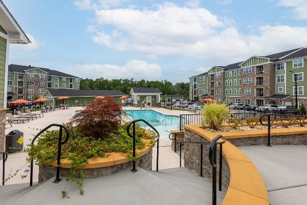 A pool area with a small tree in a planter and a wall of apartment buildings in the background at Foxwood Apartments, Raleigh-Durham, NC, 27616