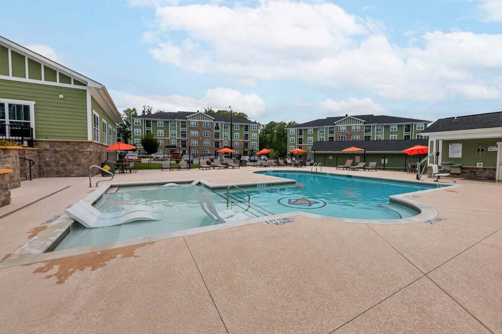 A large outdoor swimming pool surrounded by a patio and umbrellas at Foxwood Apartments, Raleigh-Durham, 27616