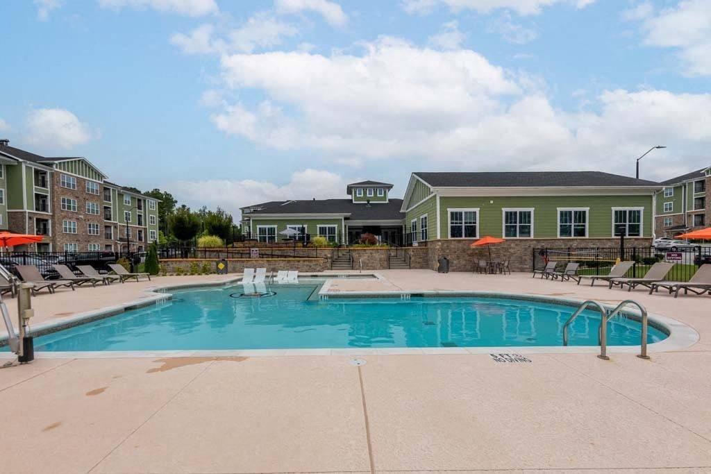 A large swimming pool surrounded by lounge chairs and umbrellas at Foxwood Apartments, Raleigh-Durham, 27616