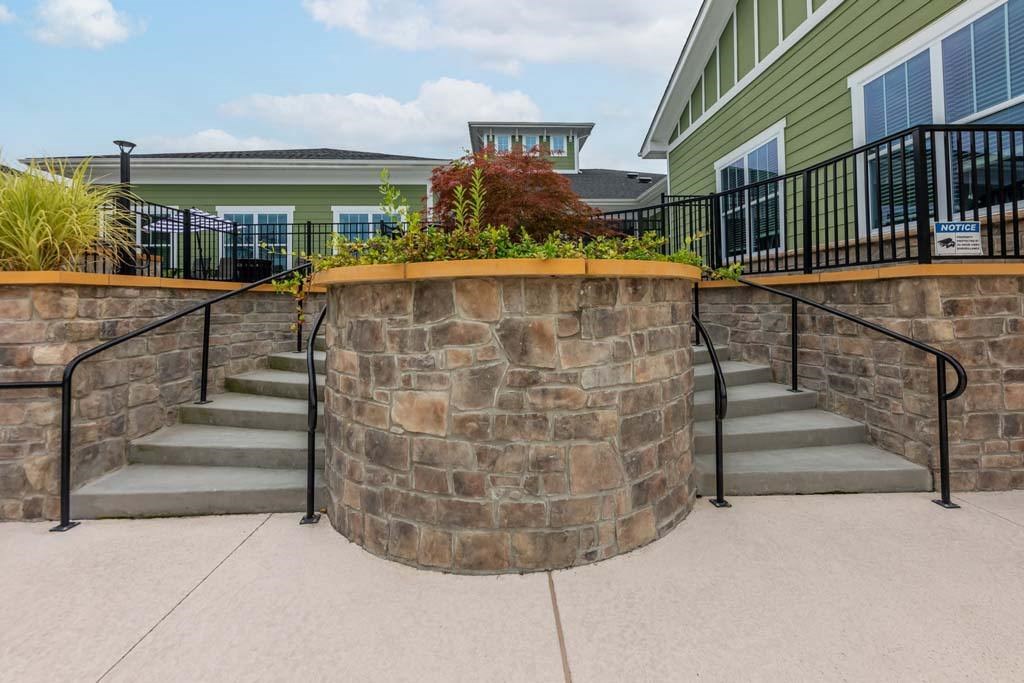A stone wall with metal railings and steps leading up to a building at Foxwood Apartments, Raleigh-Durham, NC