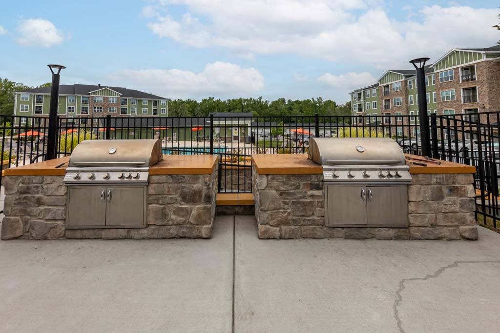 Two stone BBQs are in front of a black fence at Foxwood Apartments, Raleigh-Durham, North Carolina