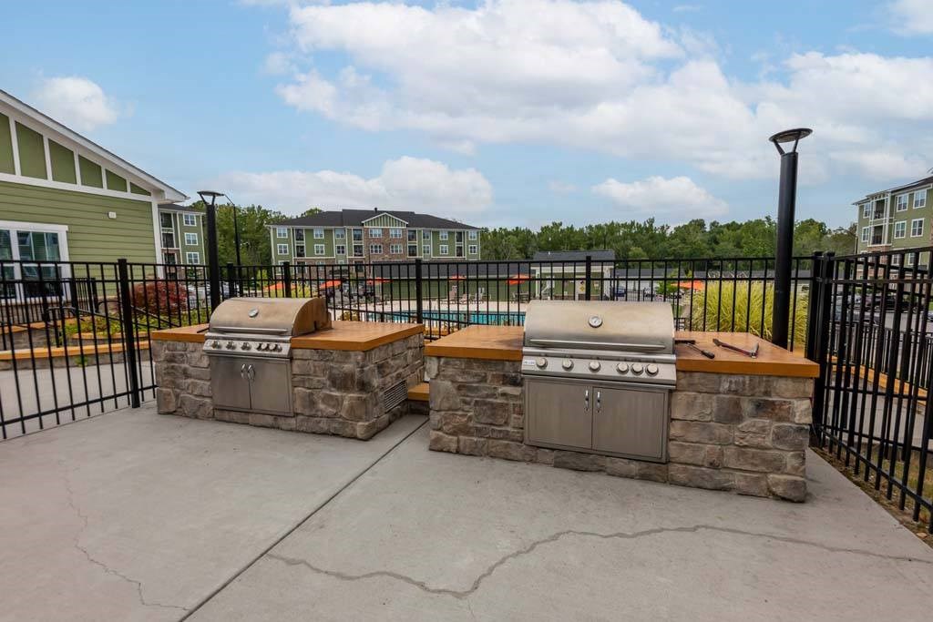 A stone fireplace with a grill on top is in the middle of a concrete patio at Foxwood Apartments, Raleigh-Durham, NC