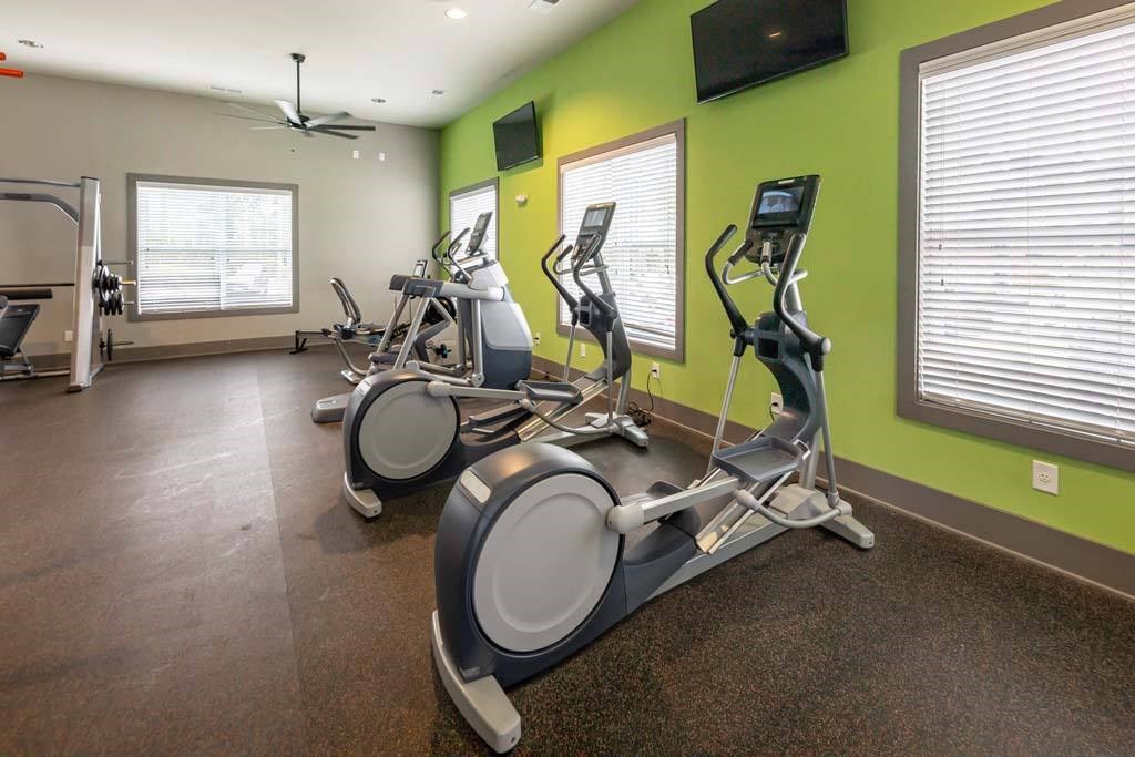 A gym with exercise bikes and a television on the wall at Foxwood Apartments, North Carolina, 27616