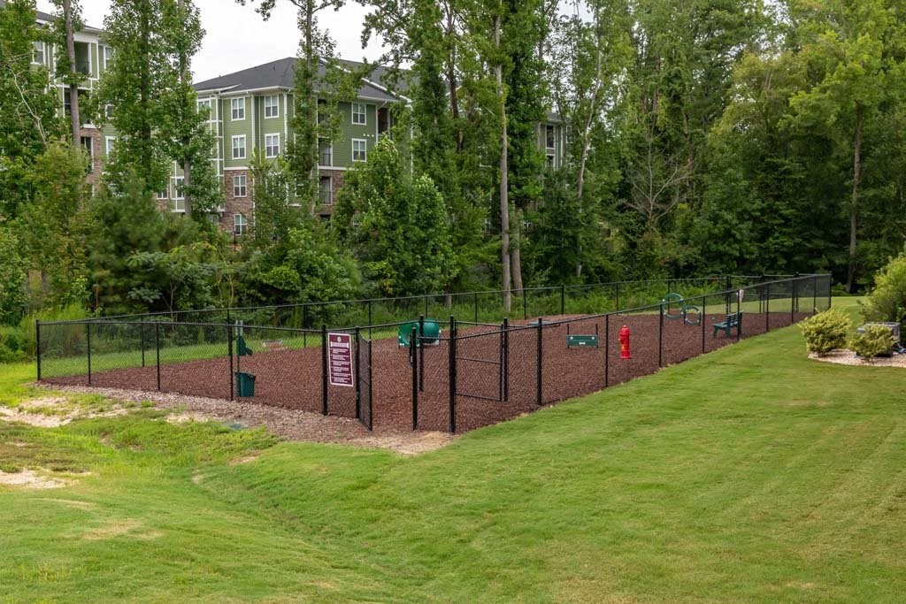 A green lawn with a fence and a sign at Foxwood Apartments, Raleigh-Durham, 27616