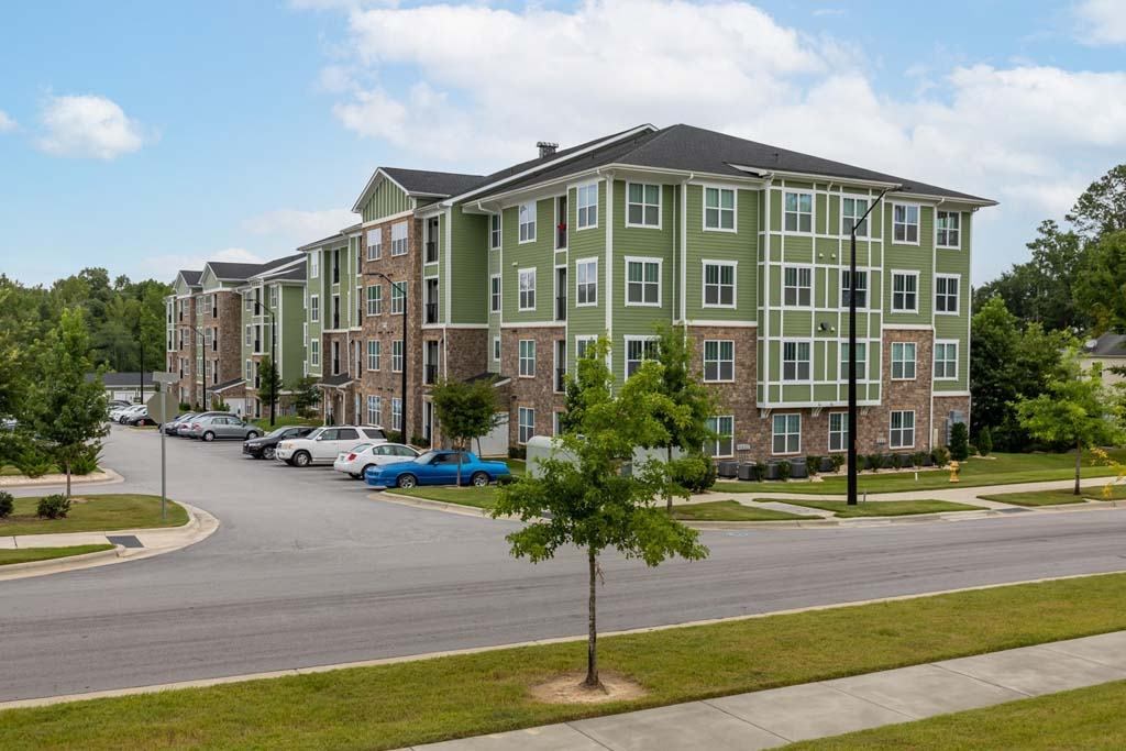 A tree stands in front of a green building at Foxwood Apartments, North Carolina
