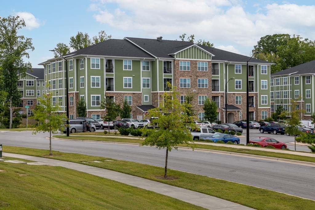 A green and beige apartment building with a parking lot in front at Foxwood Apartments, Raleigh-Durham, North Carolina