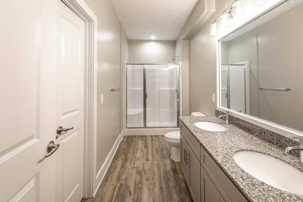 A bathroom with a toilet, sink, mirror, and shower at Foxwood Apartments, Raleigh-Durham, NC
