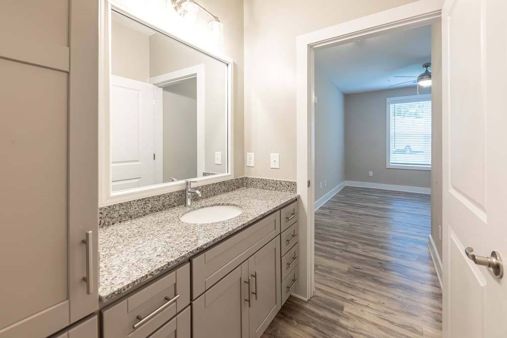 A bathroom with a sink, mirror, and wooden floors at Foxwood Apartments, North Carolina