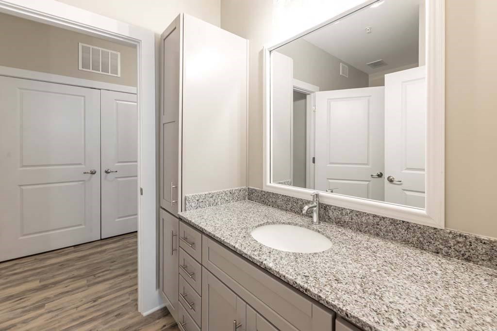 A bathroom with a sink, mirror, and wooden floors at Foxwood Apartments, Raleigh-Durham, North Carolina