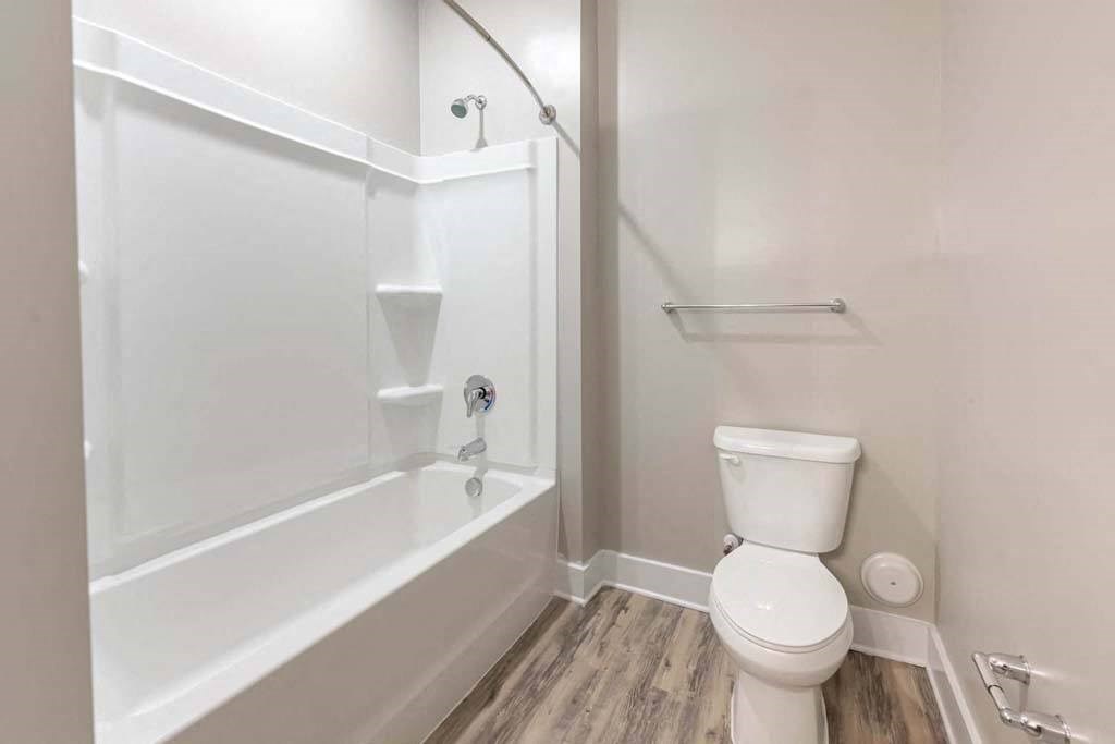 A white toilet sits next to a bathtub in a bathroom at Foxwood Apartments, North Carolina, 27616