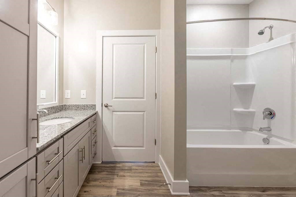 A white bathroom with a tub, sink, and mirror at Foxwood Apartments, Raleigh-Durham, NC, 27616