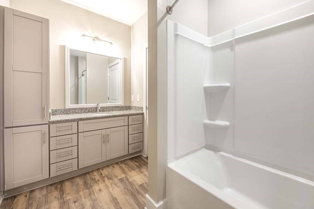 A white bathroom with a wooden floor and a white bathtub at Foxwood Apartments, Raleigh-Durham, NC
