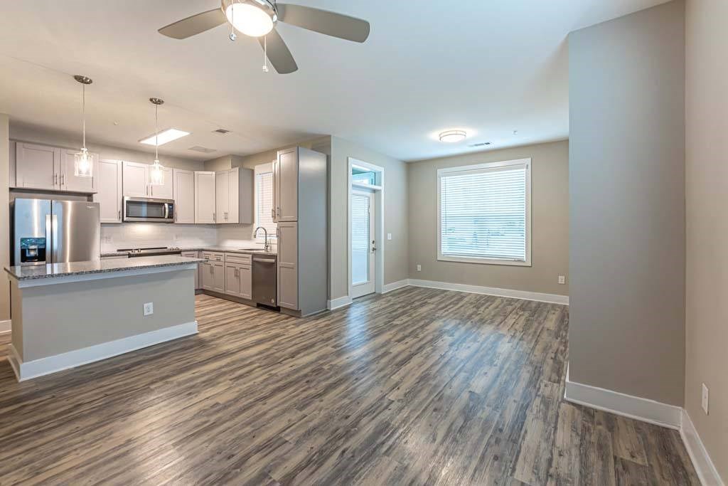A modern kitchen with a wooden floor and a ceiling fan at Foxwood Apartments, Raleigh-Durham