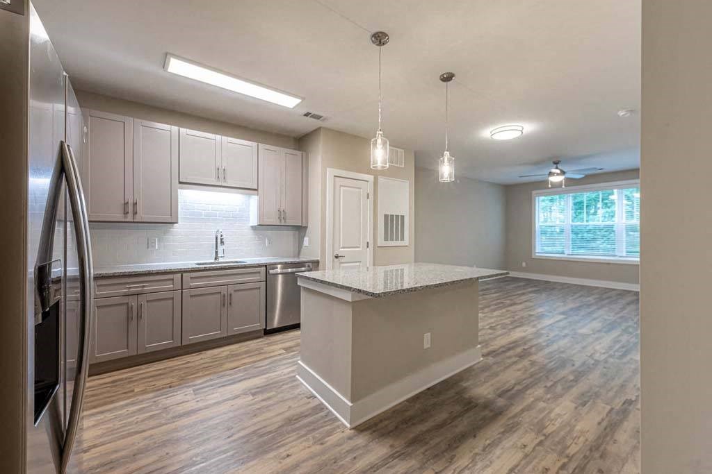 A kitchen with a refrigerator on the left and a counter with a sink at Foxwood Apartments, Raleigh-Durham, NC