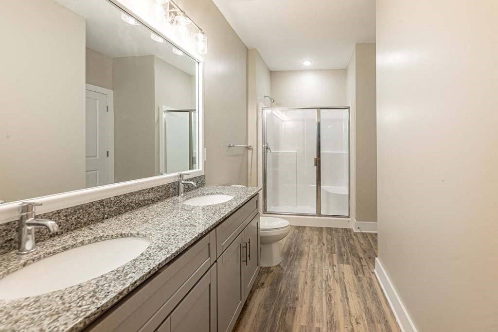A bathroom with a sink, mirror, and shower at Foxwood Apartments, Raleigh-Durham