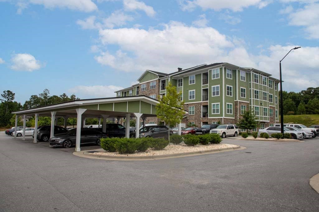 A parking lot in front of a green building at Foxwood Apartments, Raleigh-Durham, NC, 27616