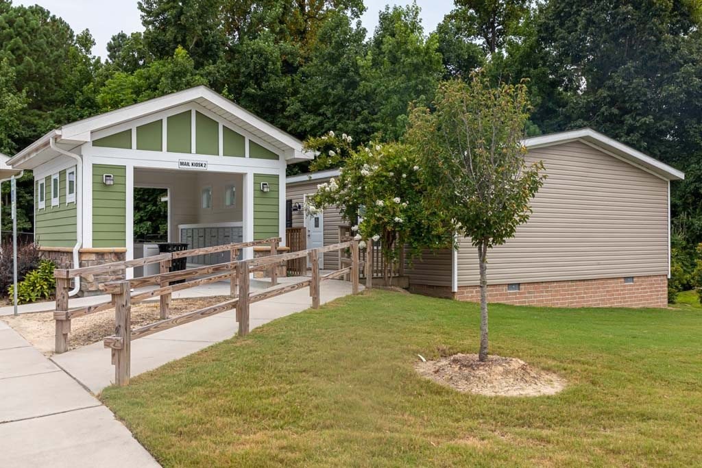 A green and white building with a porch and a tree in front of a beige building at Foxwood Apartments, Raleigh-Durham, North Carolina