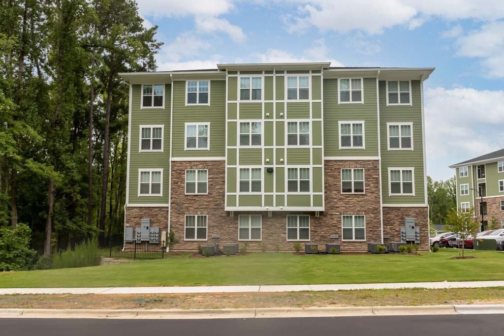 A large apartment building with a green and grey exterior at Foxwood Apartments, North Carolina, 27616