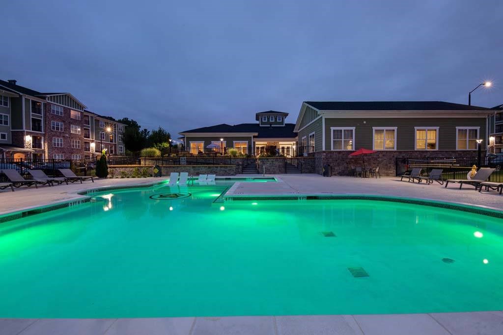 A swimming pool lit up with green lights at dusk at Foxwood Apartments, Raleigh-Durham