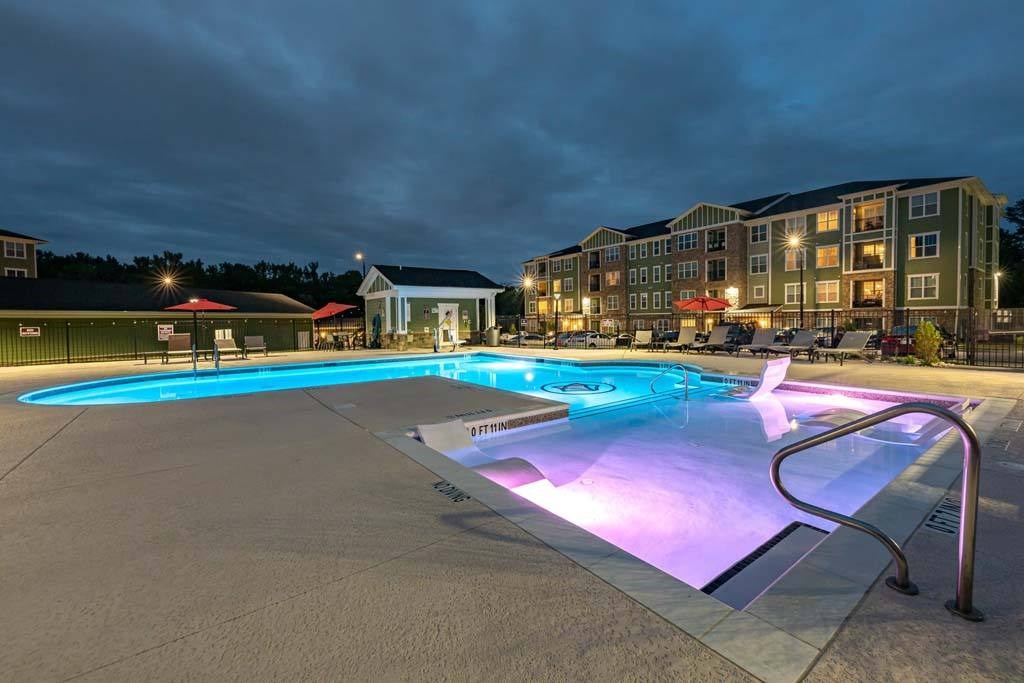 A lit up pool at night with a building in the background. at Foxwood Apartments, North Carolina, 27616