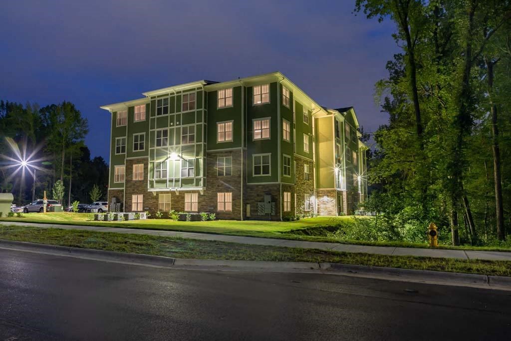 A large building with a greenish hue is illuminated at night at Foxwood Apartments, Raleigh-Durham, North Carolina
