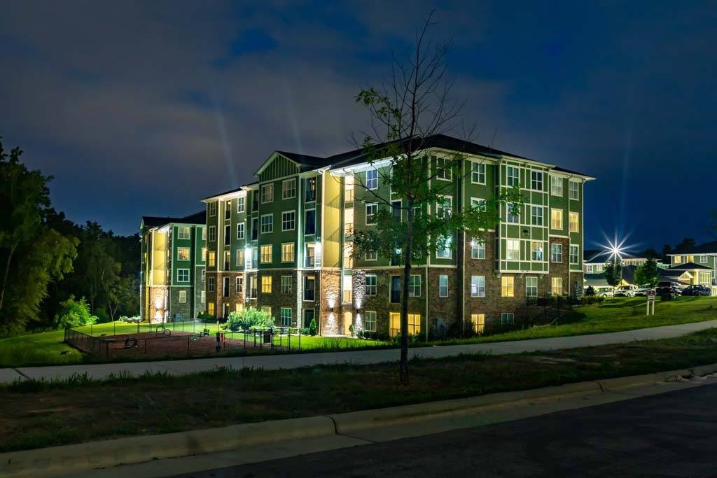 A large green building with lights on at night. at Foxwood Apartments, Raleigh-Durham, 27616