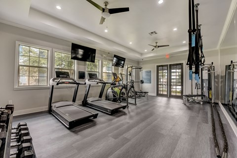 A spacious gym with treadmills, elliptical machines, and a television.