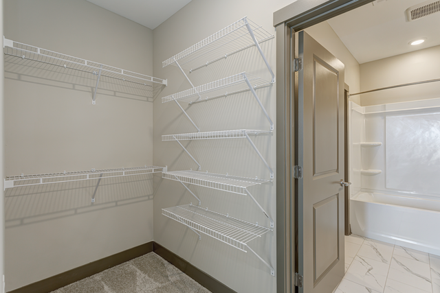 a spacious closet in a home with white walls and a white closet door